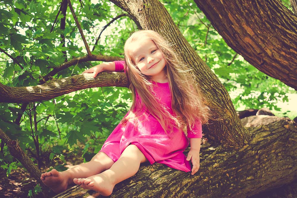 mosolygós kislány faágon ülve